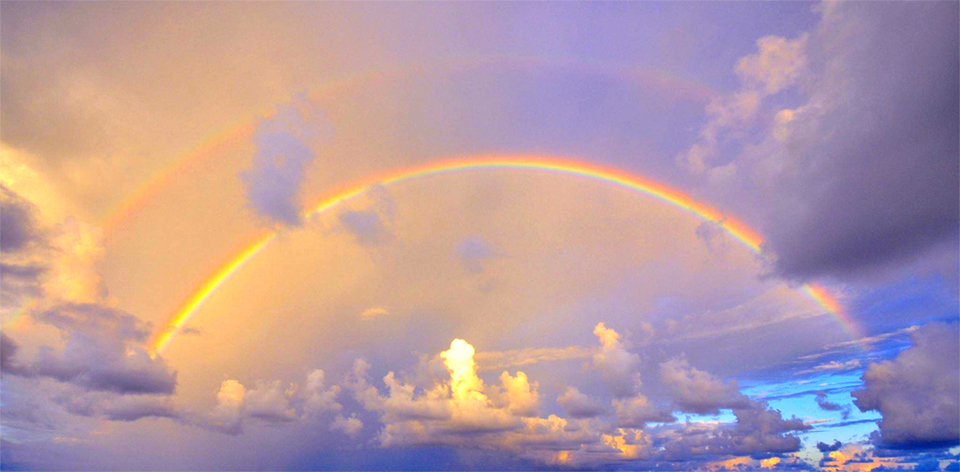 Double rainbow over golden clouds